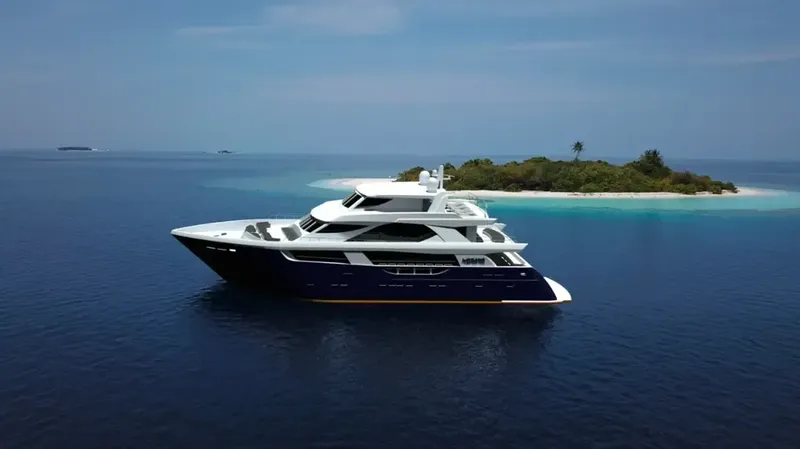 Grand yacht blanc et bleu navigue sur une mer turquoise