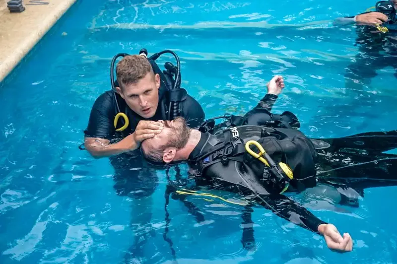 Deux plongeurs en formation, un aide l'autre dans l'eau