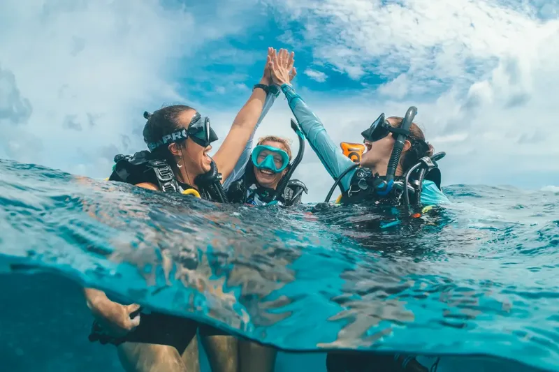 Plongeurs souriants se donnent un high-five sous la surface de l'eau