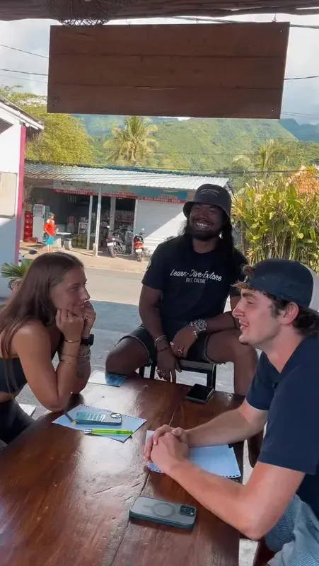 Trois personnes discutent autour d'une table en bois, ambiance décontractée