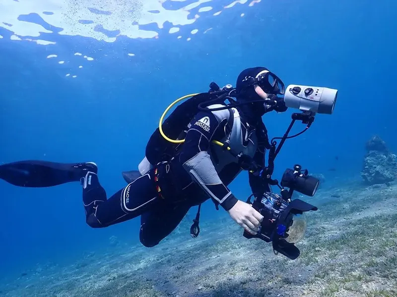 Plongeur équipé d'un appareil photo sous-marin nage dans l'eau bleue
