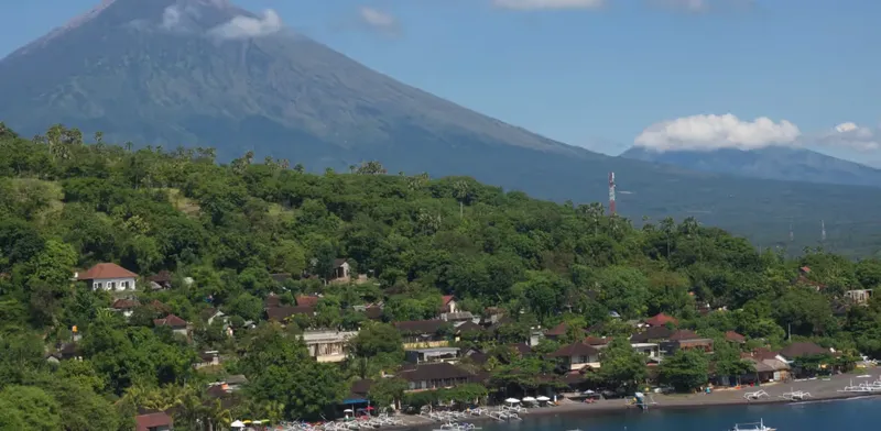 Vue d'ensemble d'un village côtier avec un volcan en arrière-plan