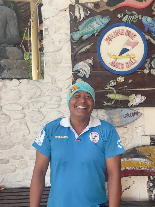 Un homme souriant portant un polo bleu et une casquette
