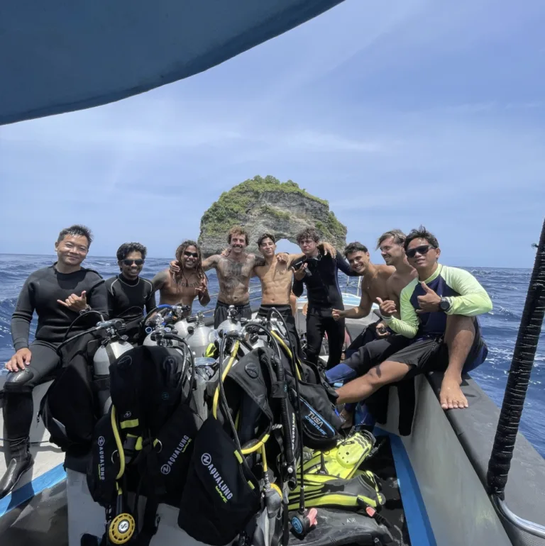 Groupe de plongeurs souriants sur un bateau en mer, équipement visible