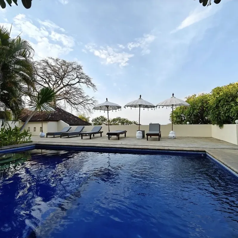 Piscine bleue avec transats et parasols, espace de détente extérieur