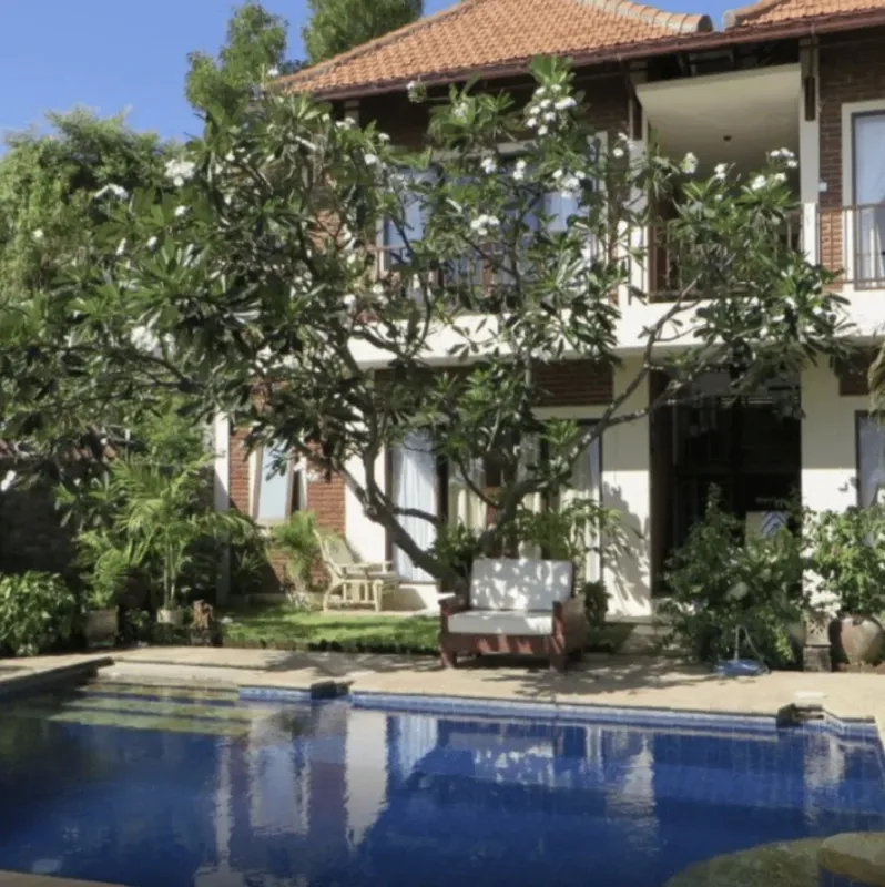 Bâtiment à deux étages avec piscine et végétation luxuriante