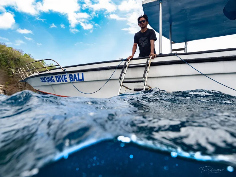 Homme sur un bateau de plongée avec vue sous-marine et ciel bleu