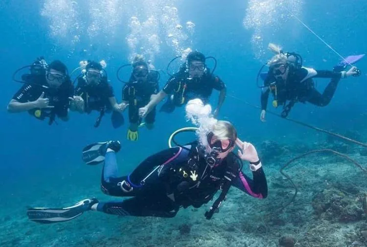 Groupe de plongeurs souriants en pleine exploration sous-marine bleu clair