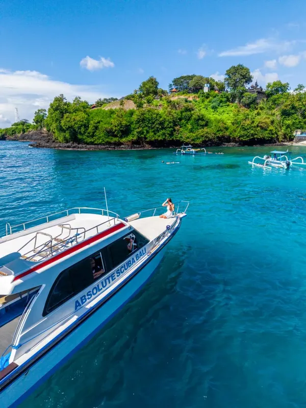 Bateau de plongée amarré dans une eau turquoise avec des personnes à bord