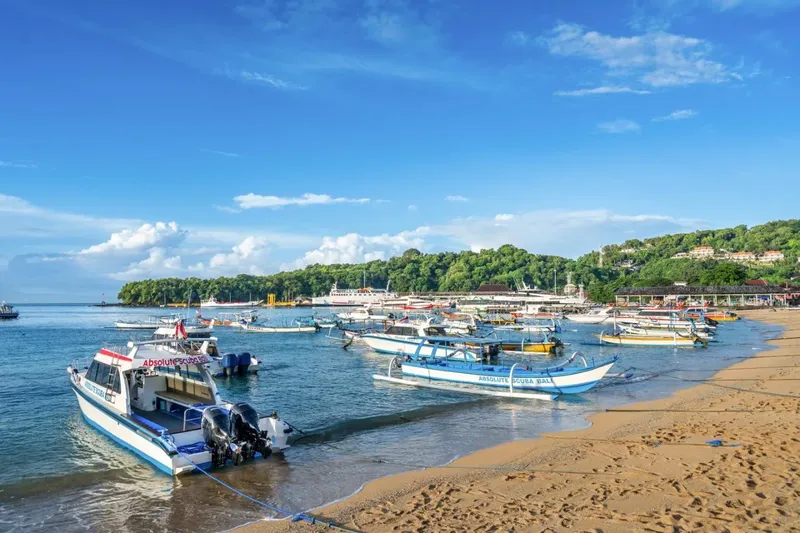 Plage avec de nombreux bateaux amarrés sous un ciel bleu clair