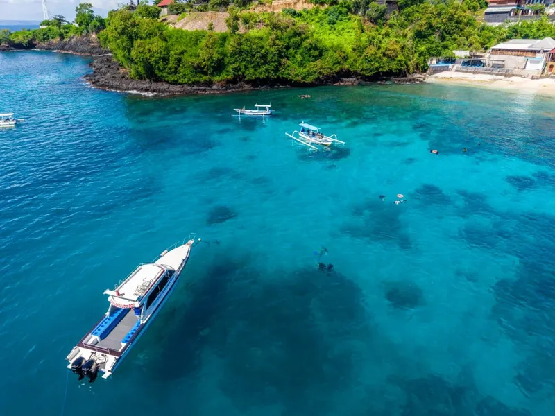 Vue aérienne de plongeurs et de bateaux dans une eau turquoise claire
