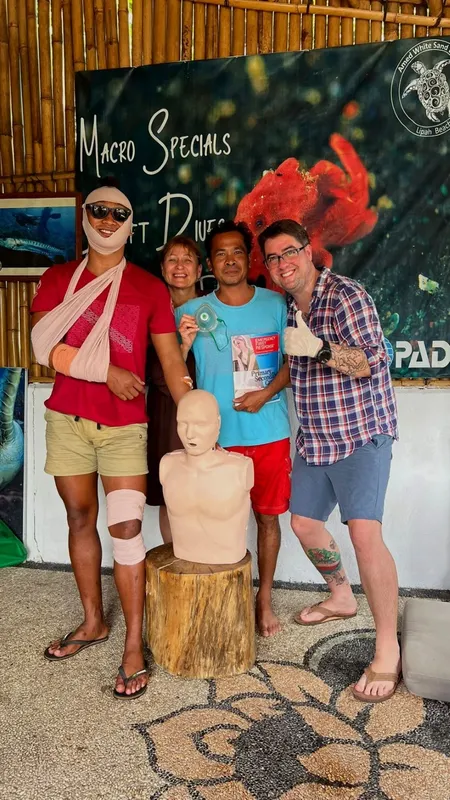 Quatre personnes souriantes posent avec un mannequin de premiers secours
