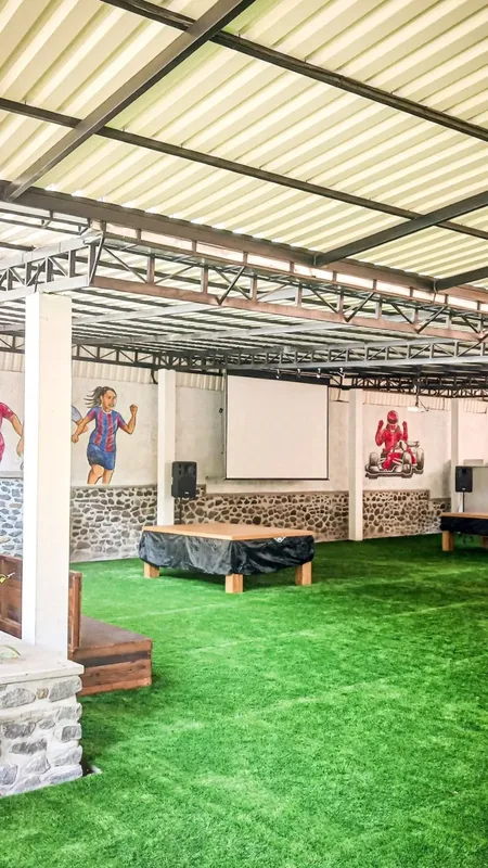 Espace intérieur avec sol vert, tables, et illustrations murales sportives