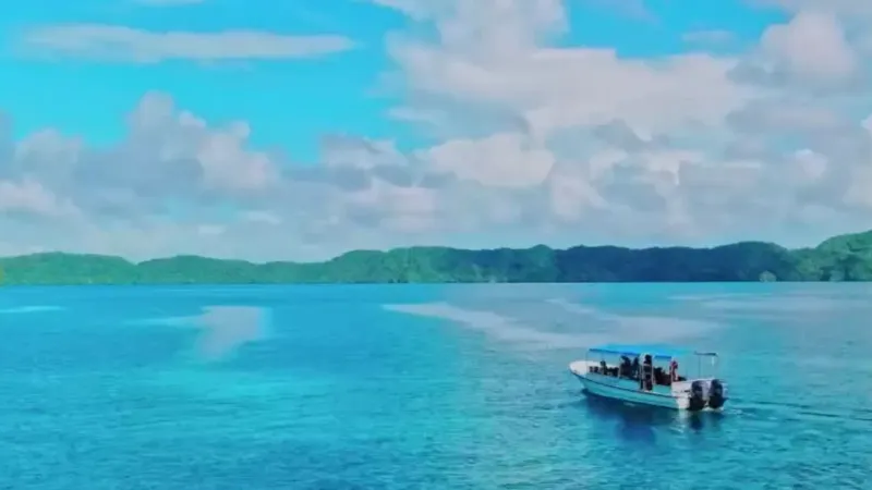 Un bateau rapide navigue sur une eau turquoise sous un ciel nuageux