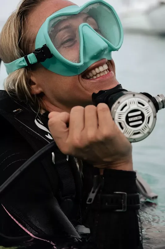 Plongeuse souriante avec masque et détendeur, prête à plonger