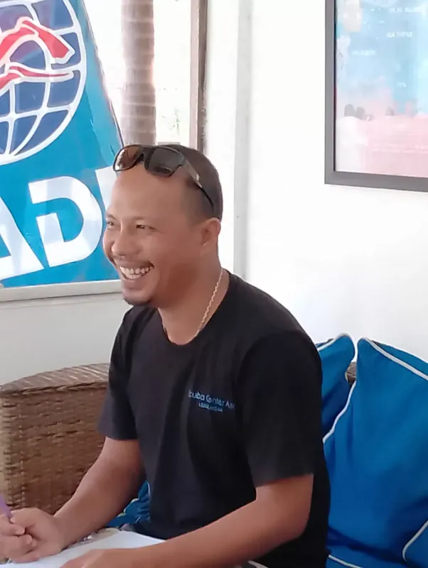 Homme souriant assis sur un canapé bleu dans un intérieur lumineux