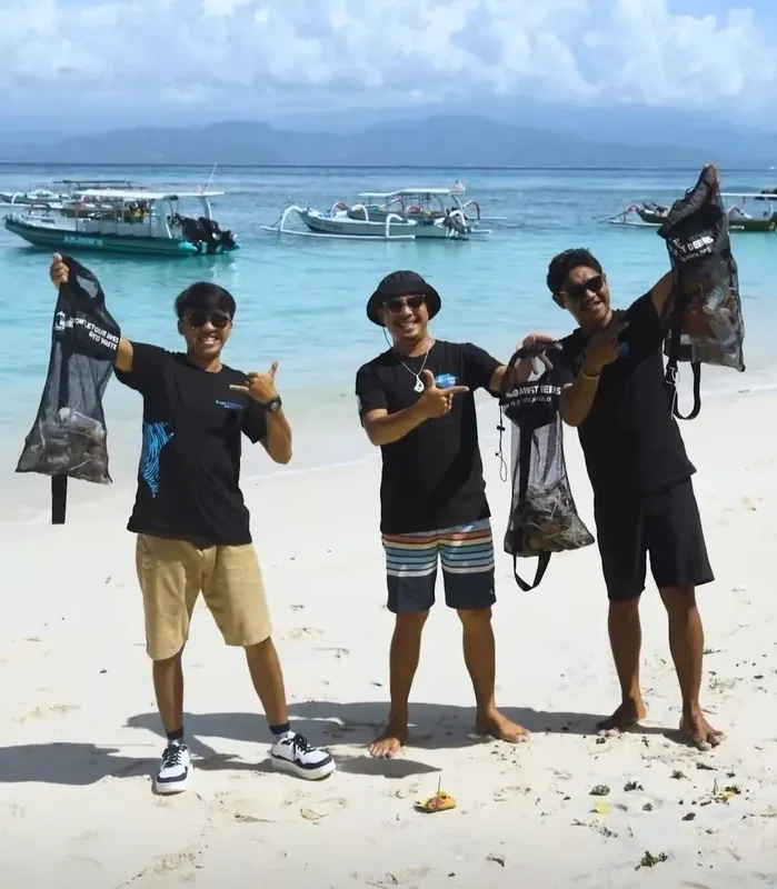Trois personnes souriantes sur une plage avec équipement de plongée
