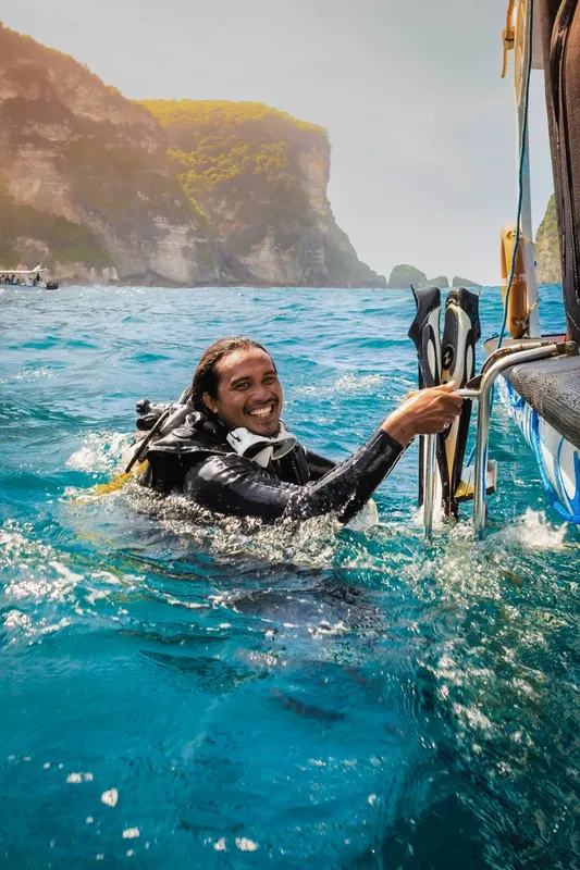 Plongeur souriant sortant de l'eau avec palmes et équipement
