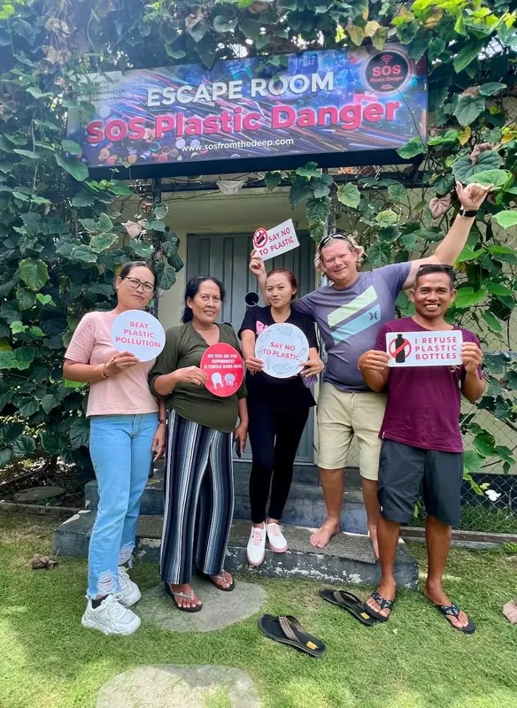 Quatre personnes souriantes tiennent des pancartes contre la pollution plastique