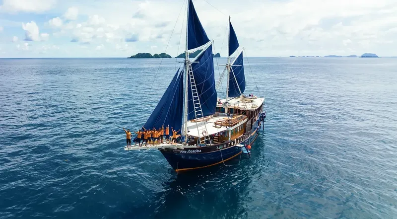 Grand voilier bleu en mer avec un groupe de personnes à bord