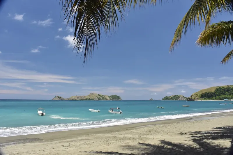 Plage de sable fin avec bateaux et eau turquoise ensoleillée