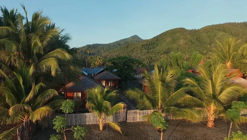 Bâtiments du centre de plongée entourés de végétation tropicale et montagnes