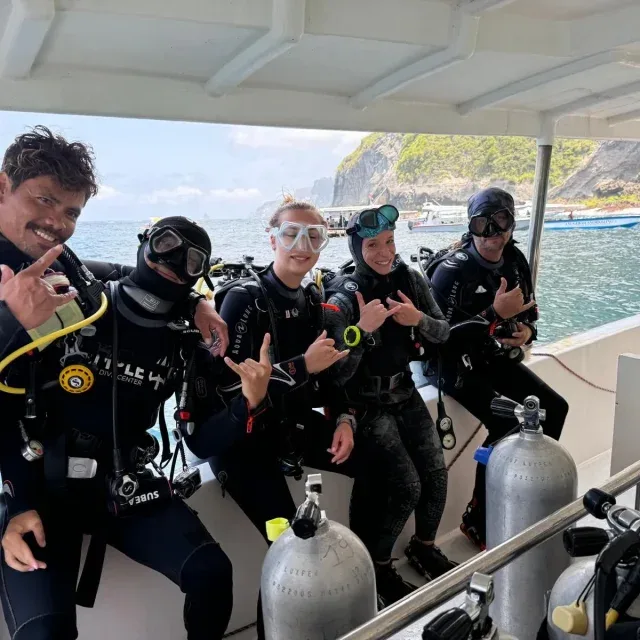 Plongeurs souriants sur un bateau, équipés et prêts à plonger