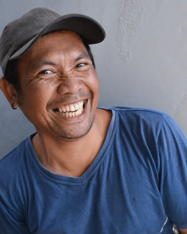 Homme souriant portant une casquette et un t-shirt bleu