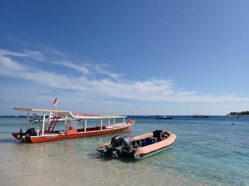 Bateaux traditionnels et semi-rigide échoués sur une plage tropicale ensoleillée