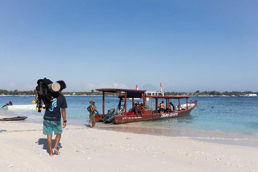 Plage ensoleillée avec un bateau de plongée et des plongeurs