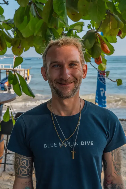 Portrait d'un homme souriant avec un t-shirt bleu et la mer en arrière-plan