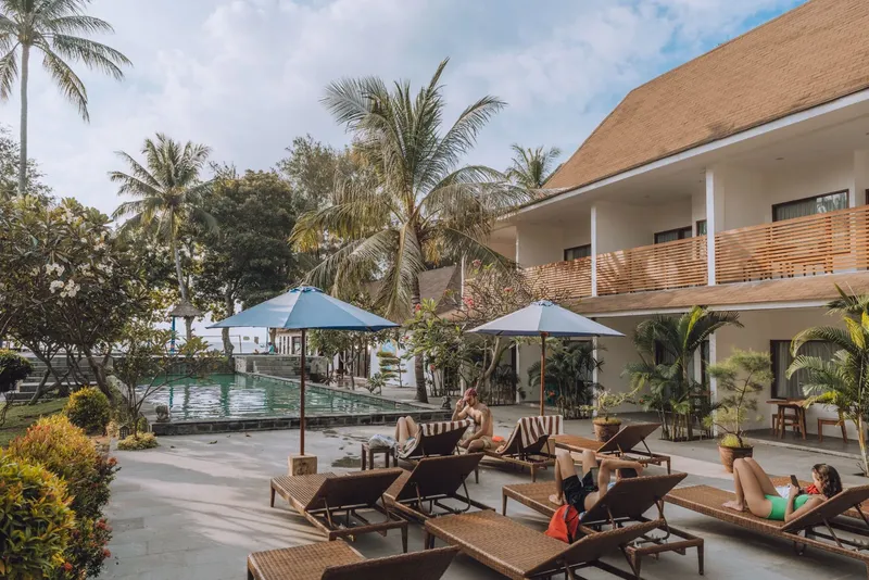 Personnes se relaxent au soleil près d'une piscine et d'un bâtiment
