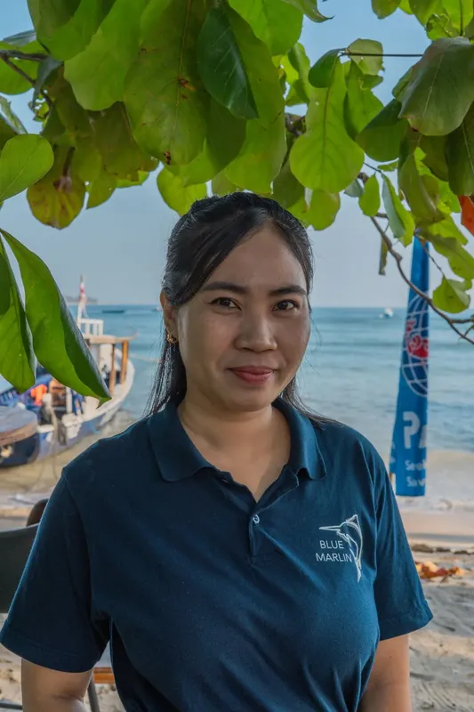 Portrait d'une femme souriante devant des bateaux et la mer