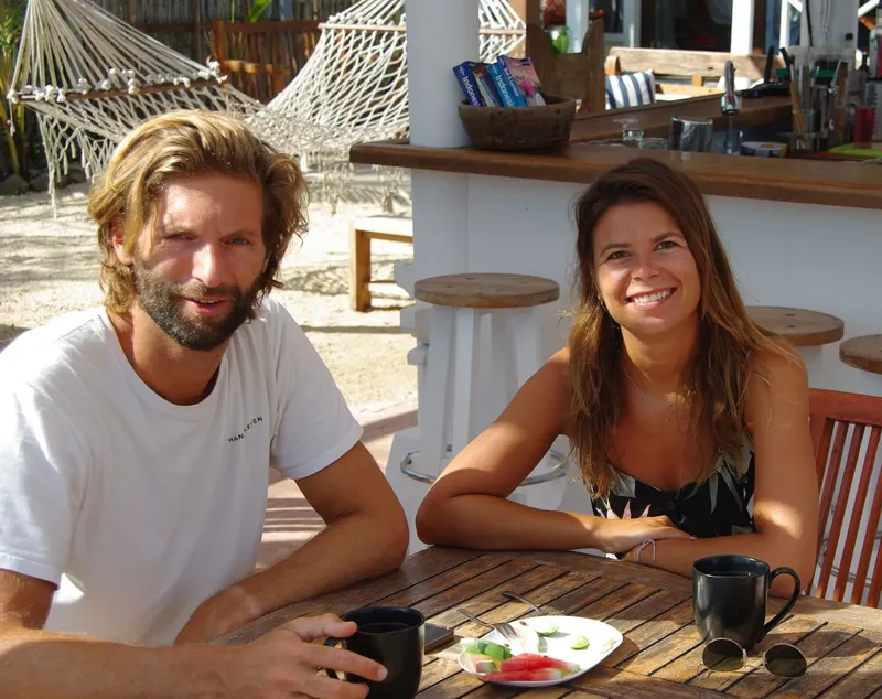 Deux personnes souriantes assises à une table en extérieur