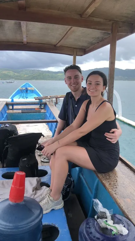 Couple souriant assis sur un bateau de plongée bleu et blanc