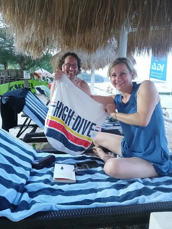 Deux personnes souriantes présentent une serviette avec l'inscription High-Dive