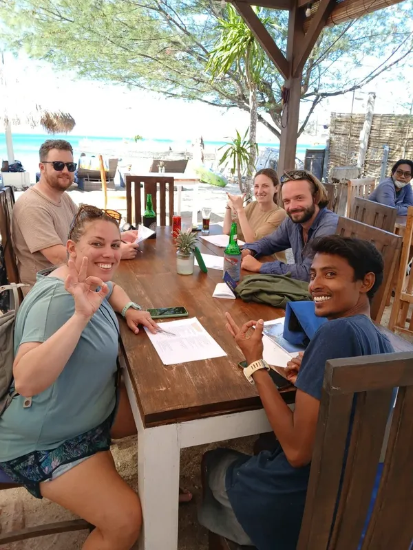 Groupe de personnes souriantes assises autour d'une table en bois