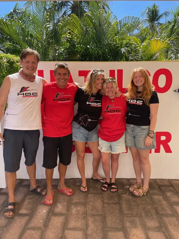 Cinq personnes souriantes posent devant une grande banderole rouge