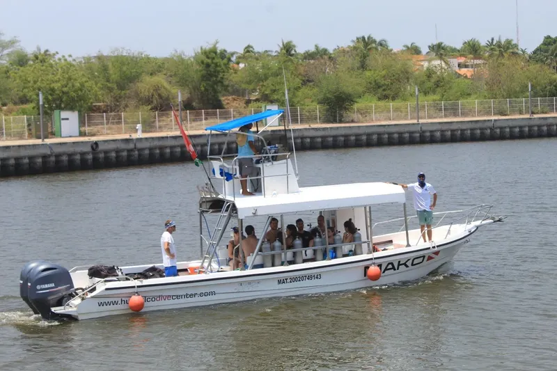 Bateau de plongée rempli de personnes naviguant sur un canal ensoleillé