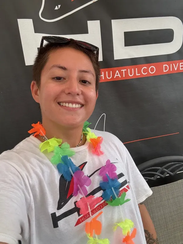 Portrait souriant d'une personne portant un collier coloré et un t-shirt
