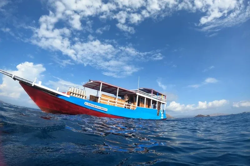 Bateau de plongée bleu et rouge sur l'eau avec des passagers