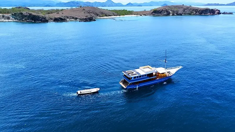 Vue aérienne d'un bateau de plongée bleu sur une mer calme