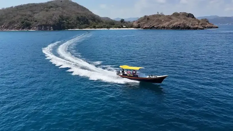 Bateau de plongée navigue sur une mer bleue vers une côte rocheuse