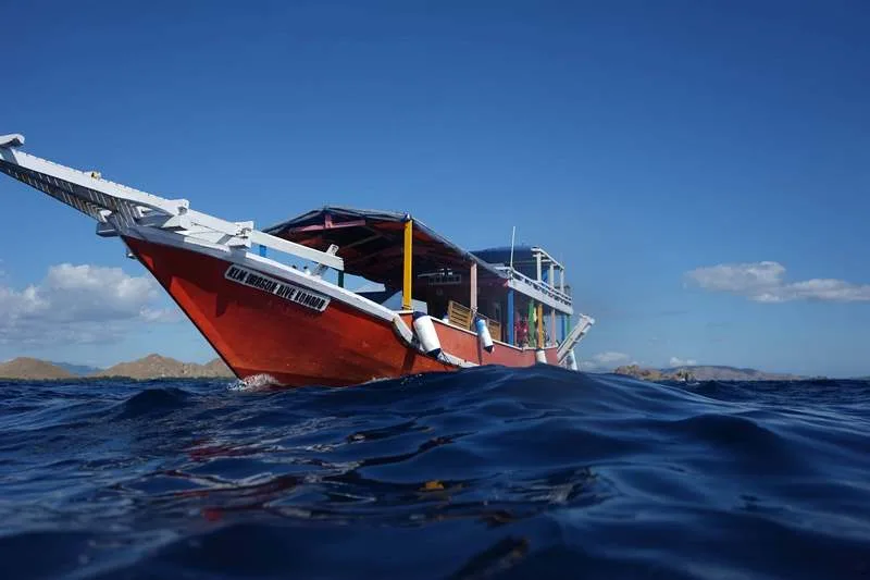 Bateau de plongée orange sur l'eau, avec des plongeurs à bord