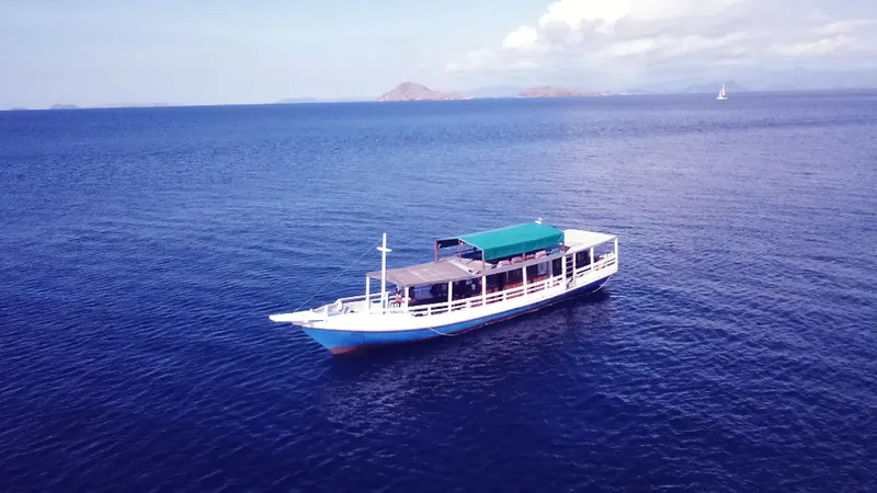 Bateau de plongée blanc et bleu navigue sur une mer calme