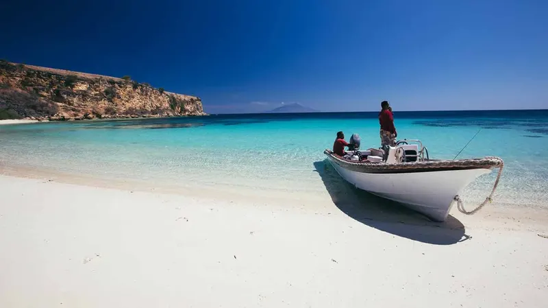 Deux personnes à bord d'un bateau sur une plage de sable blanc
