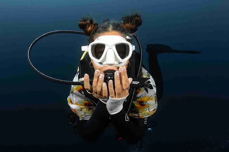 Plongeuse souriante avec masque et détendeur dans l'eau bleue