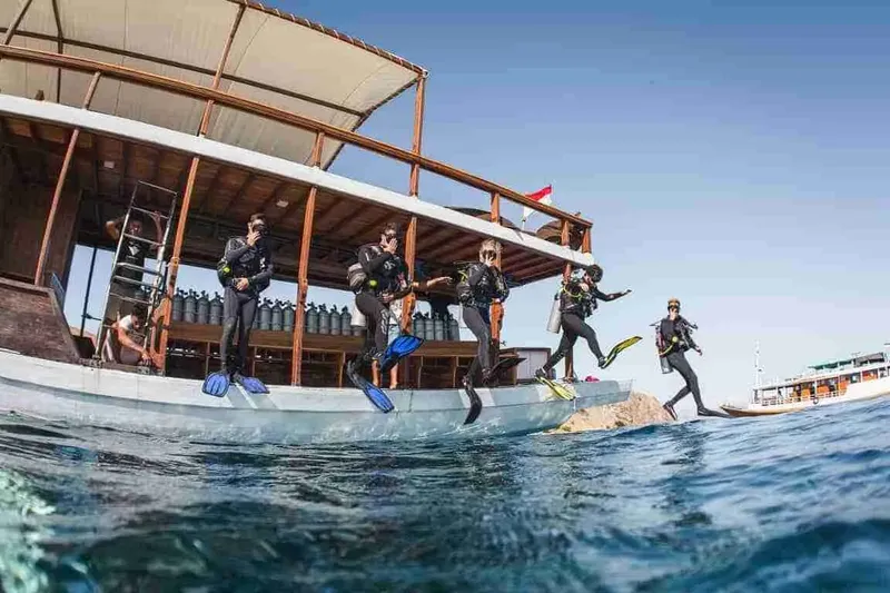 Plongeurs s'apprêtent à sauter d'un bateau traditionnel en mer