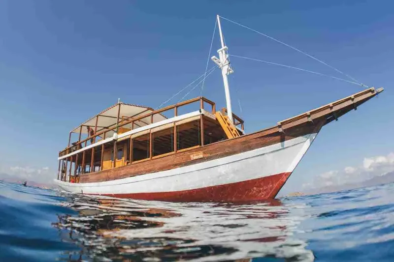 Bateau de plongée traditionnel en bois flottant sur l'eau calme