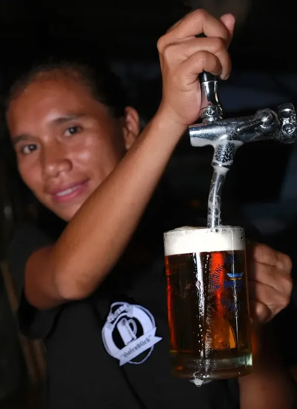 Un homme verse de la bière dans un grand verre transparent